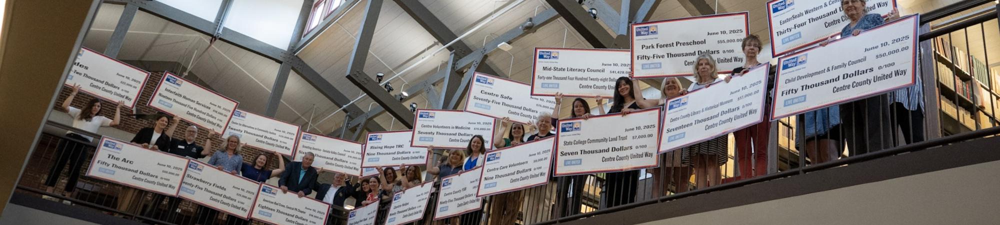 Partner Agency Representatives holding large checks 